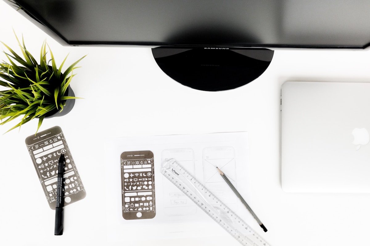 Bureau de travail avec écran d'ordinateur, plante verte, accessoires de bureau.
