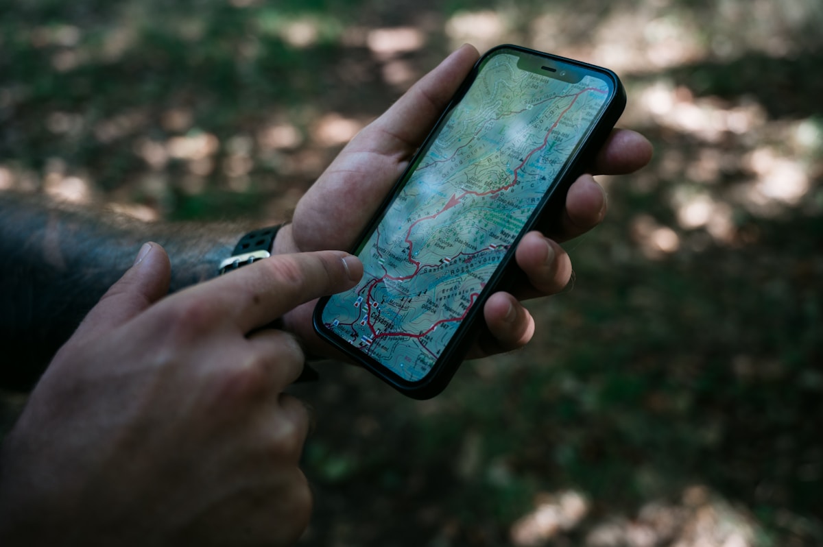 Smartphone affichant une carte topographique dans un environnement forestier.