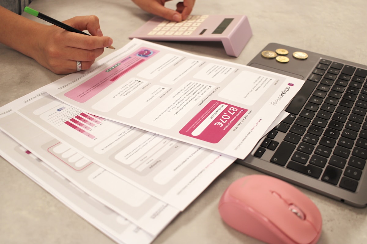Formulaires, calculatrice, souris d'ordinateur et documents sur un bureau.