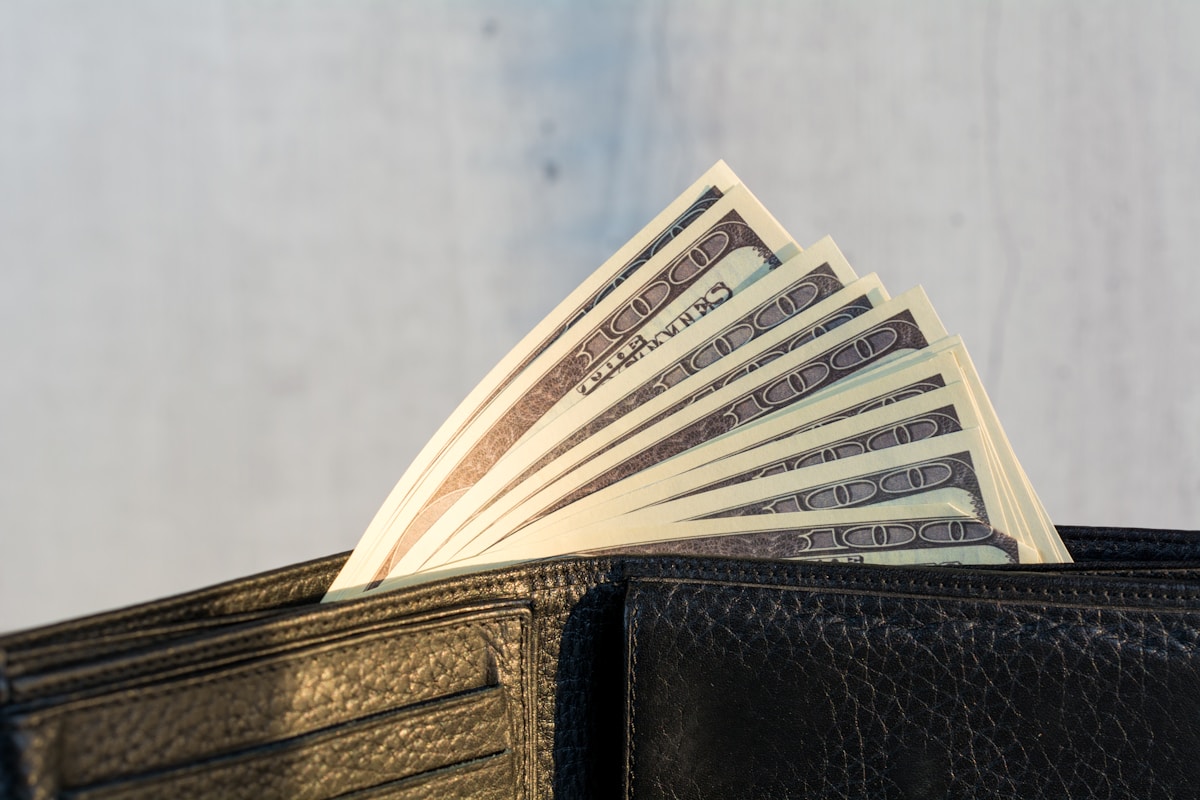 Portefeuille en cuir noir avec billets de banque en dollars américains.