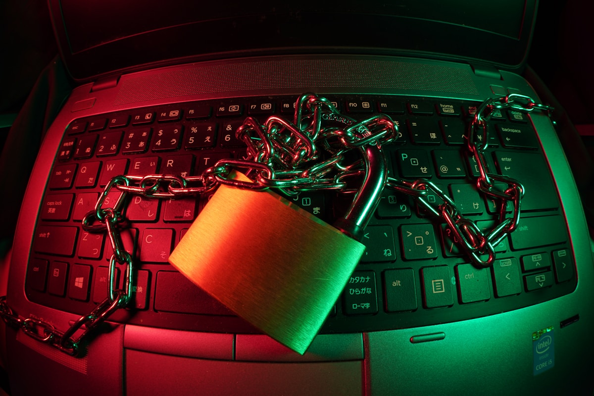 Ordinateur portable rouge avec cadenas vert et chaînes métalliques.