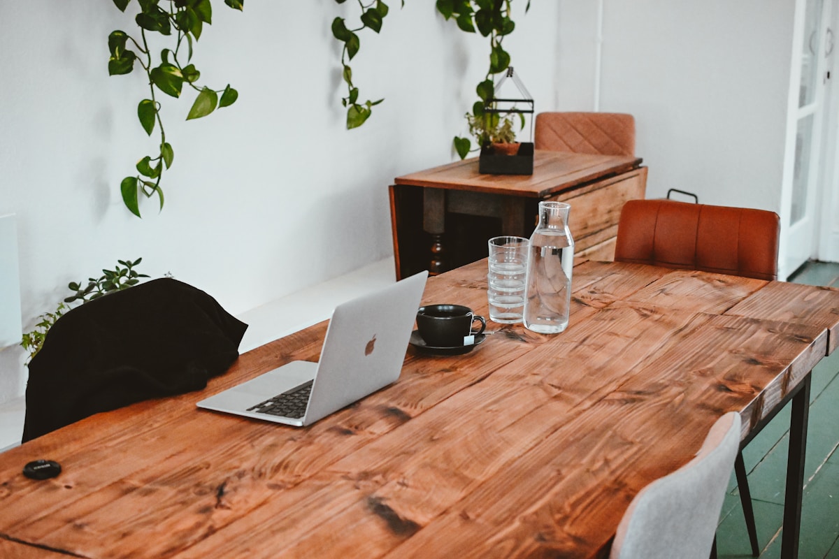 Espace de travail confortable avec table en bois, ordinateur portable et plantes.