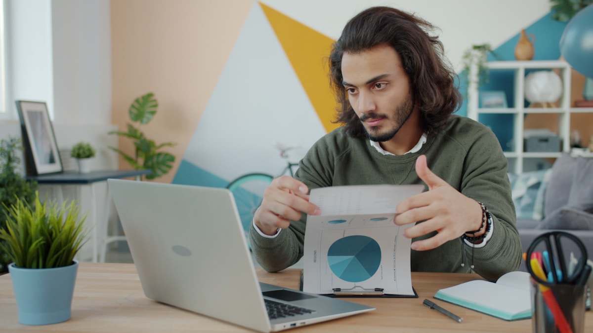 Un homme concentré analysant des données sur un ordinateur portable dans un bureau moderne.