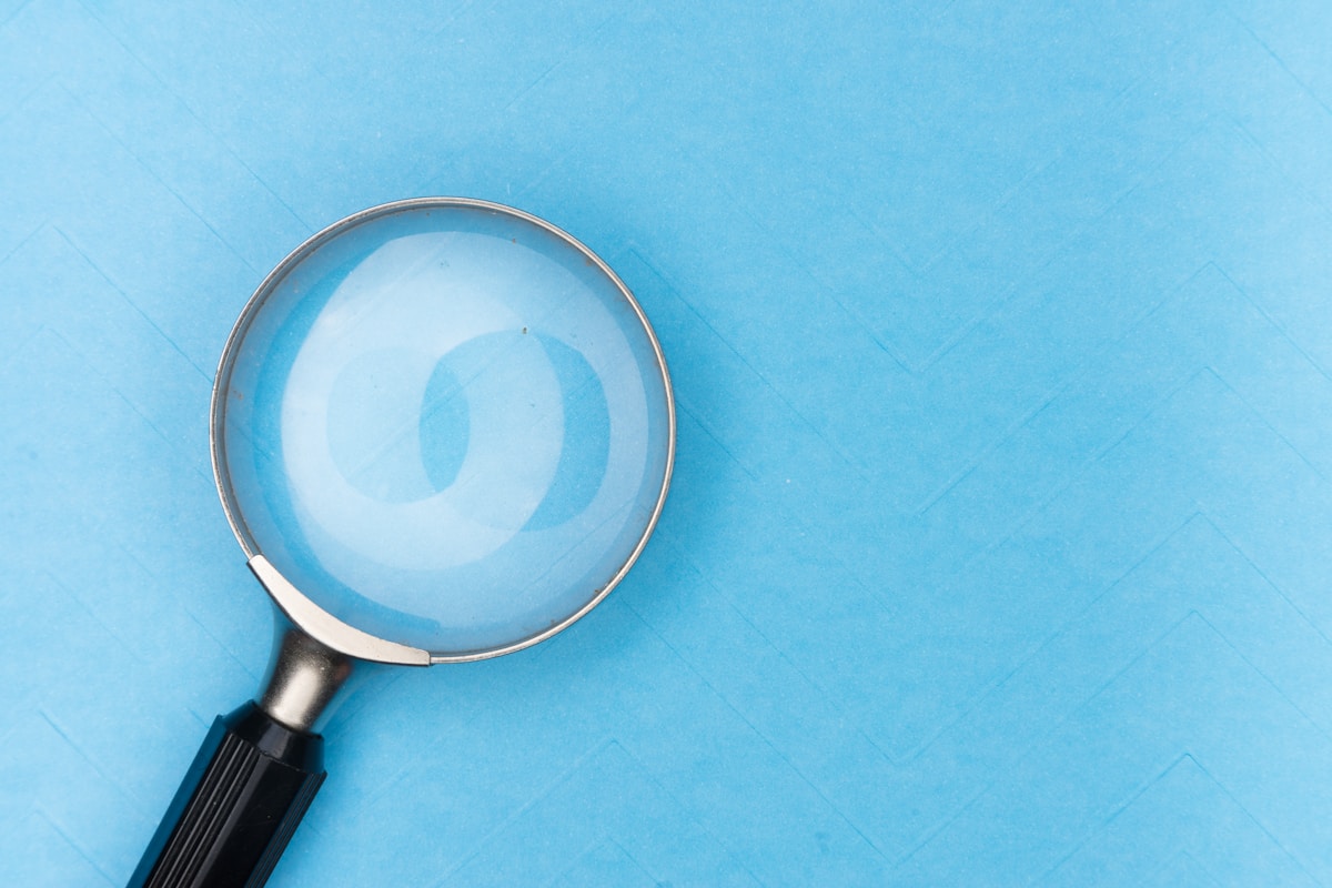 Loupe en métal sur fond bleu avec un motif spiralé.