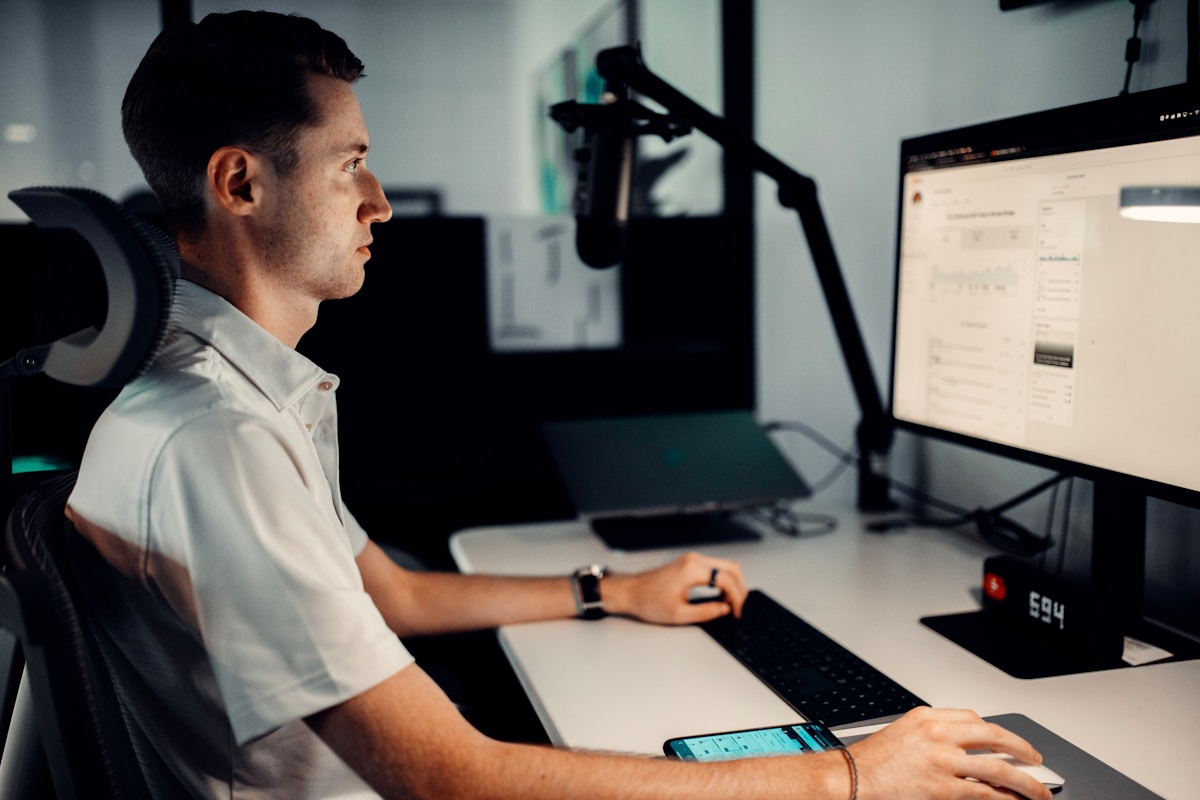Homme travaillant sur un ordinateur dans un bureau sombre.