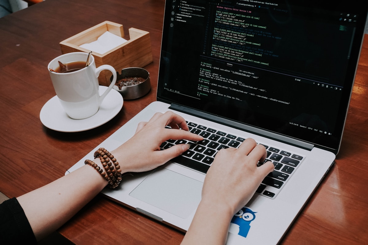 Ordinateur portable, tasse de café, code informatique, mains tapant sur le clavier.