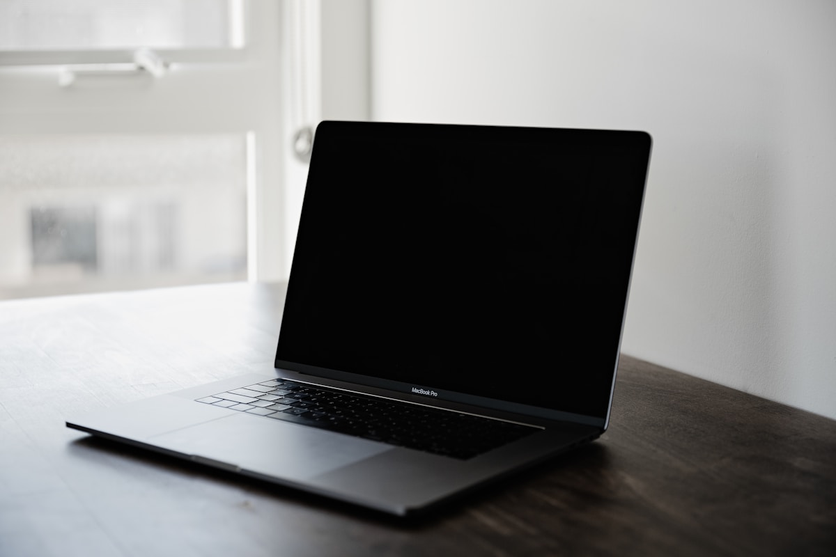 Ordinateur portable noir sur un bureau en bois.