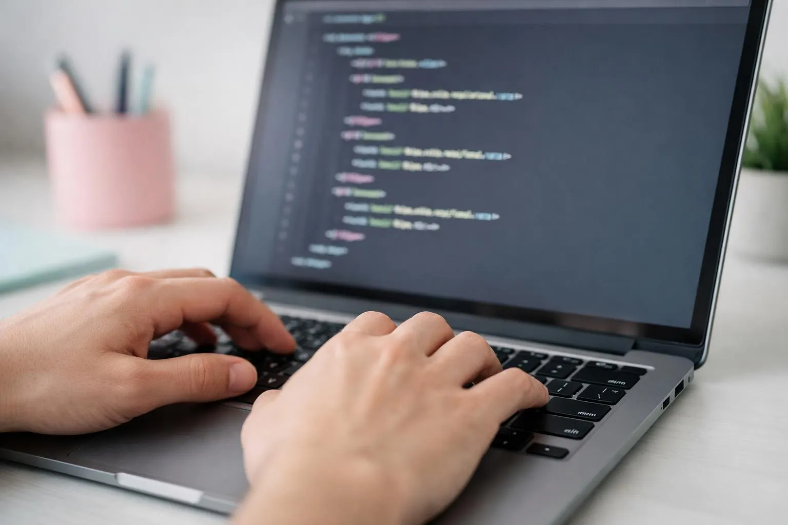 Mains d'un développeur tapant sur un clavier d'ordinateur portable affichant du code.