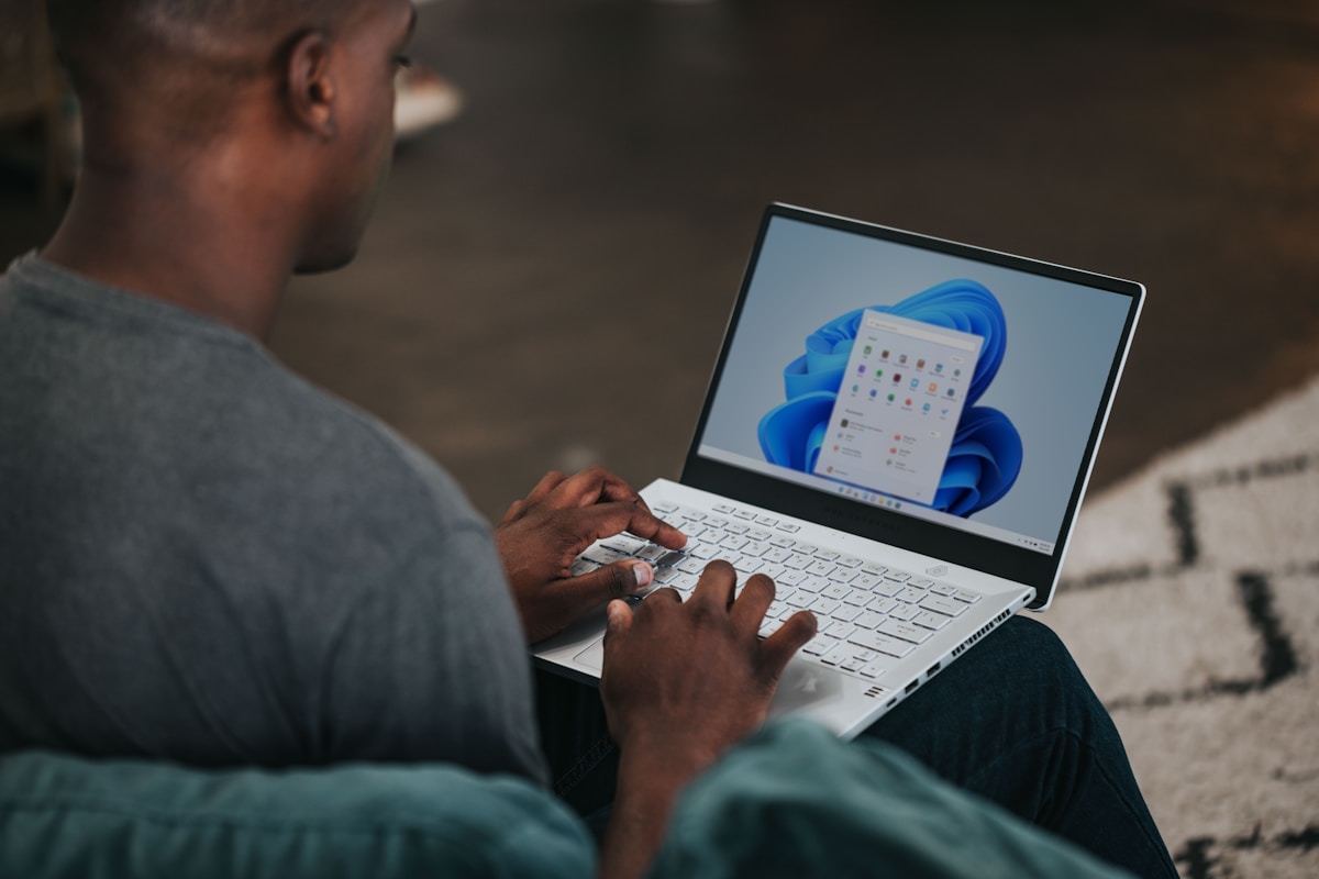 Homme utilisant un ordinateur portable avec une interface Windows 11 affichée.