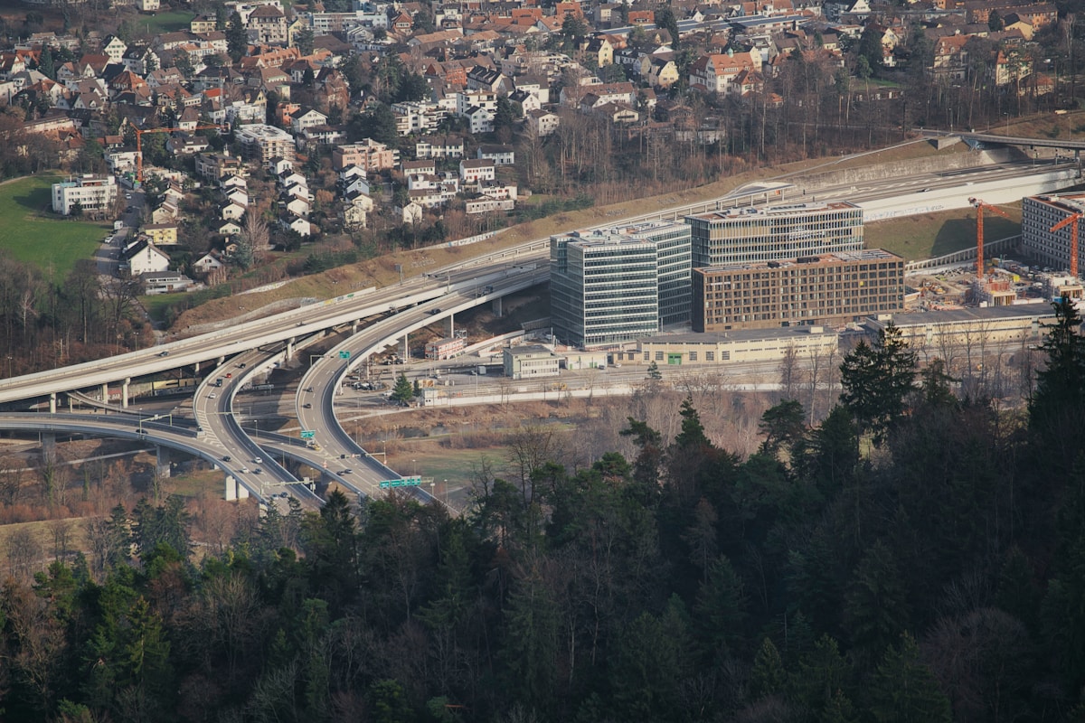 Paysage urbain avec autoroute, bâtiments et forêt.