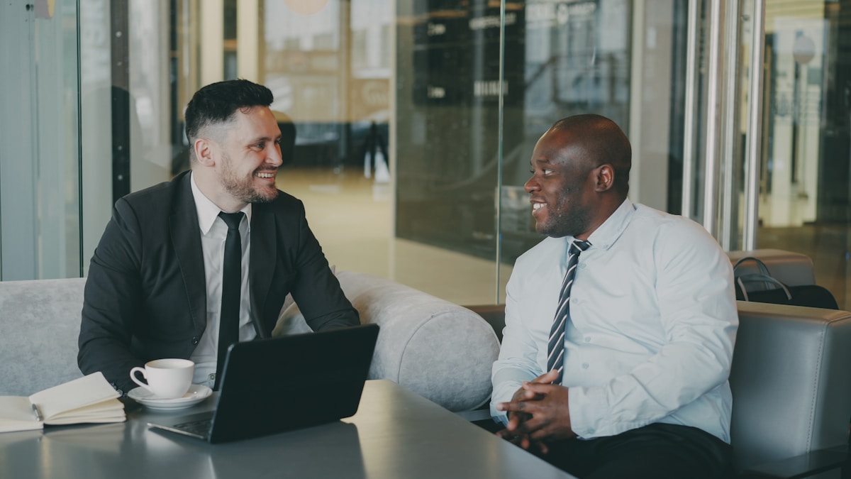 Deux hommes d'affaires souriants discutant dans un bureau moderne.