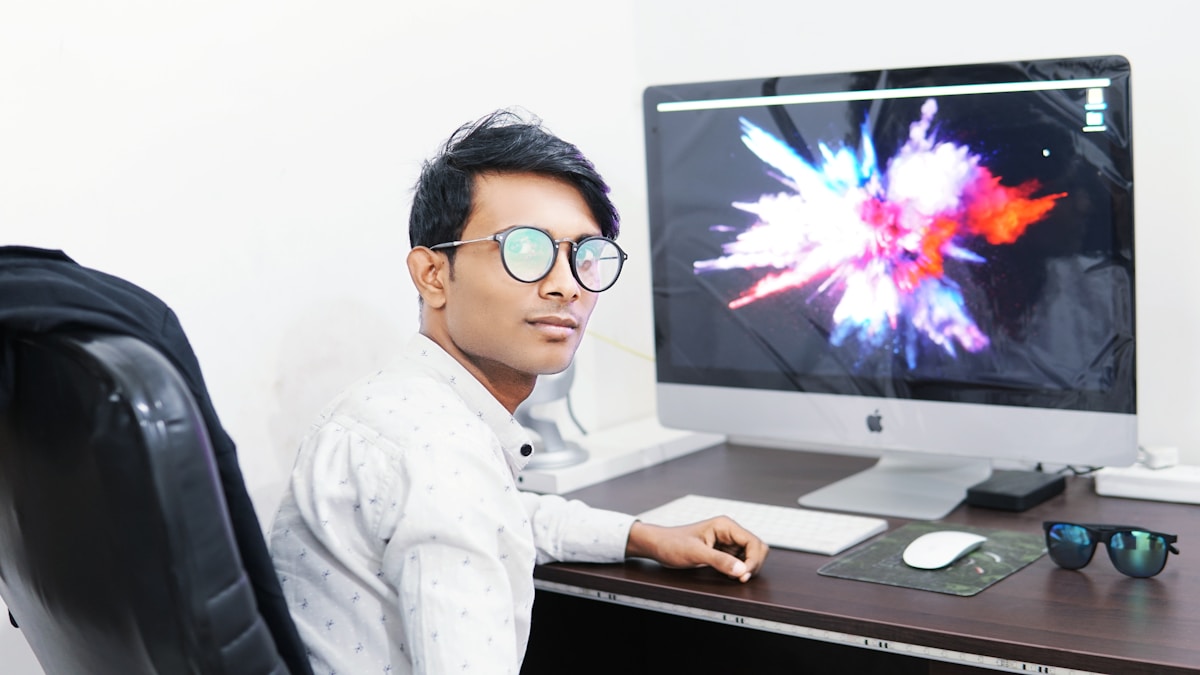 Homme asiatique travaillant sur un ordinateur avec un écran affichant une explosion colorée.