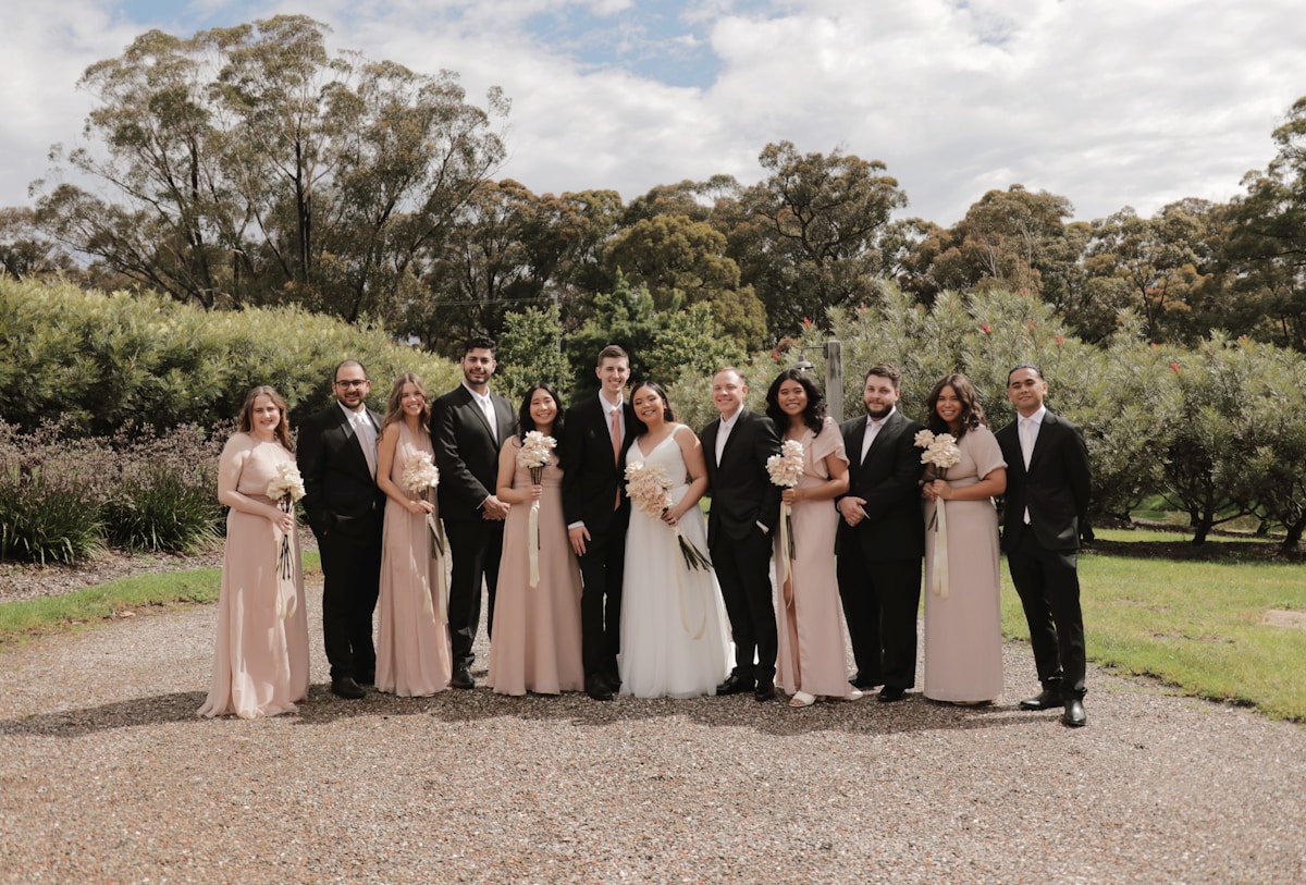 Groupe de personnes en tenue de mariage dans un cadre naturel.
