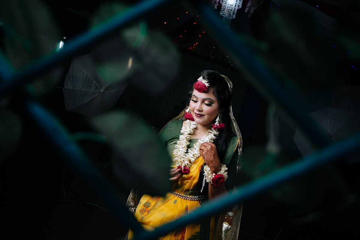 Femme en costume traditionnel indien, fleurs dans les cheveux, souriant.