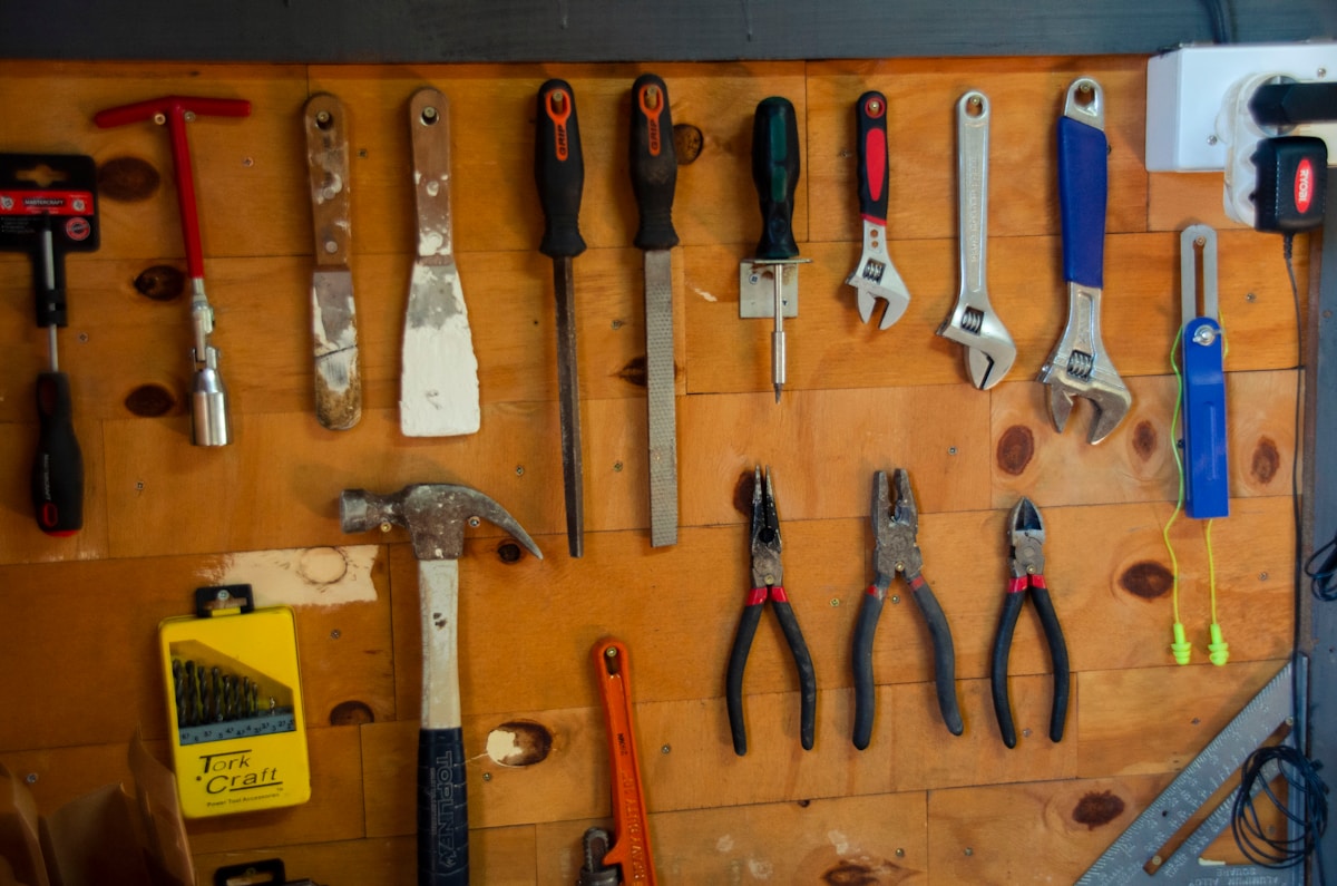 Outils de bricolage et d'artisanat suspendus sur un mur en bois.