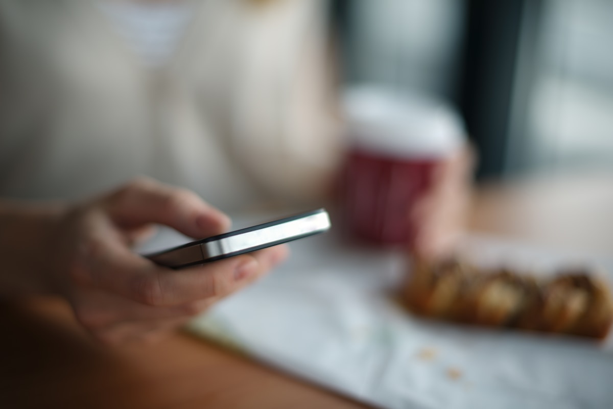 Personne utilisant un téléphone portable sur une table avec de la nourriture.