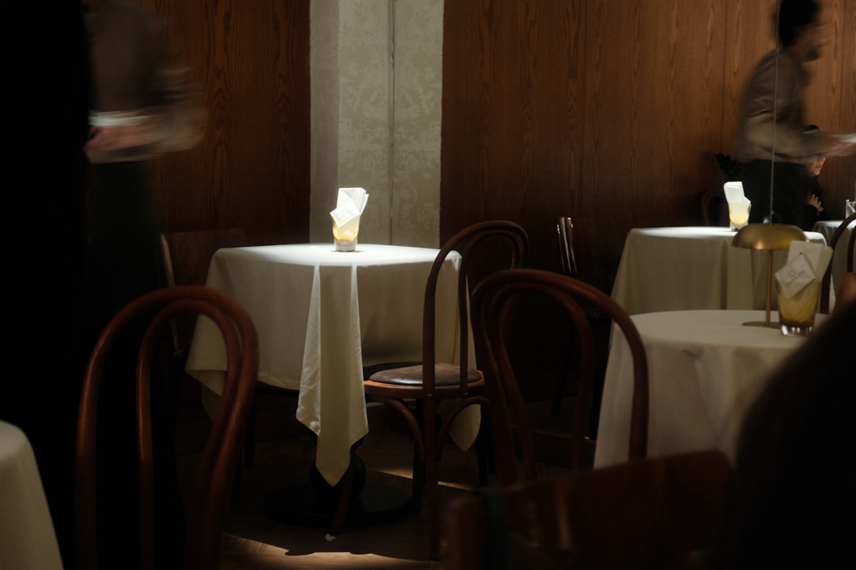 Table ronde avec chaises en bois dans un restaurant sombre.