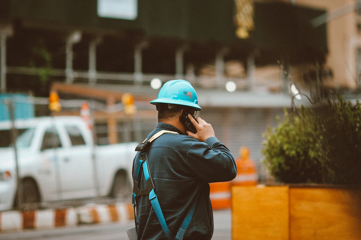 Ouvrier du bâtiment en uniforme bleu, casque de sécurité avec drapeau américain, sur un chantier.