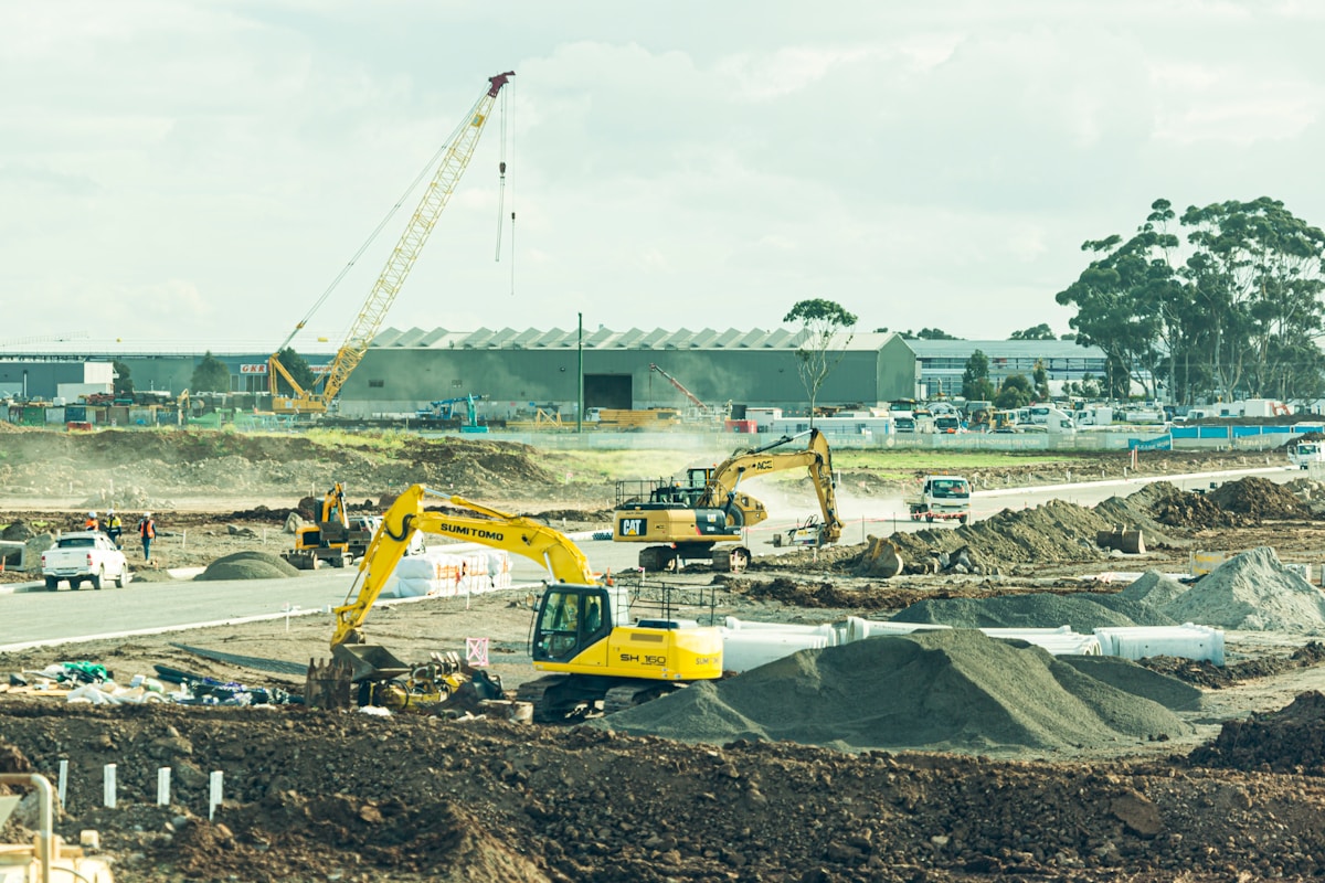 Chantier de construction avec grues, pelleteuses et camions.