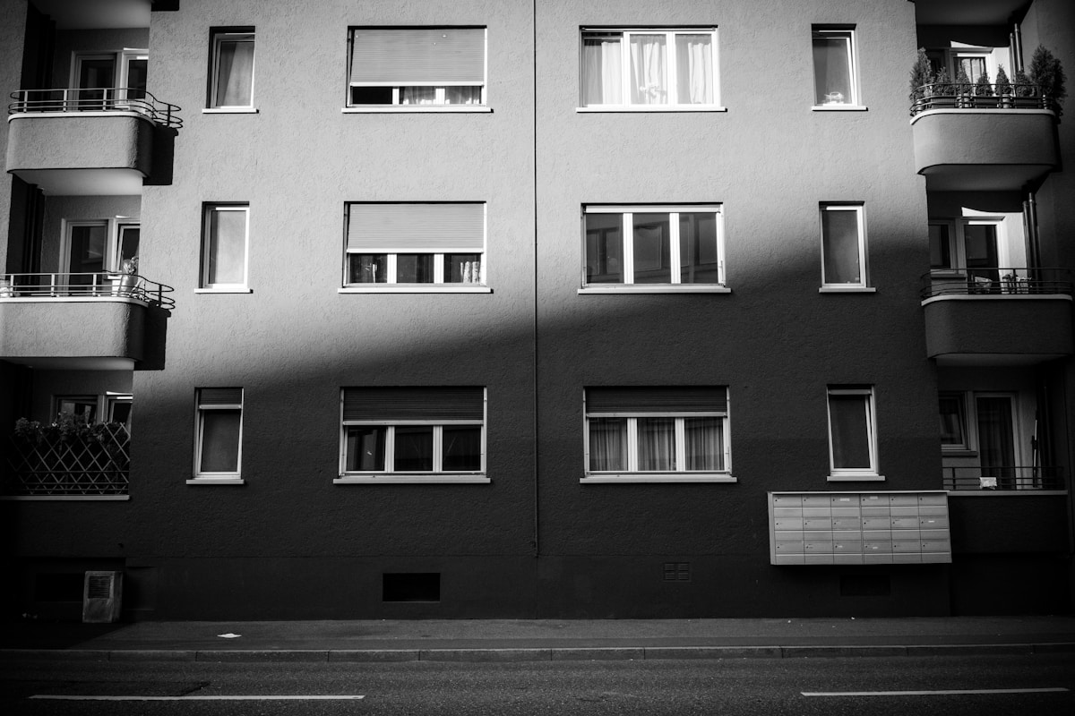 Immeuble d'appartements en noir et blanc avec balcons et boîtes aux lettres.