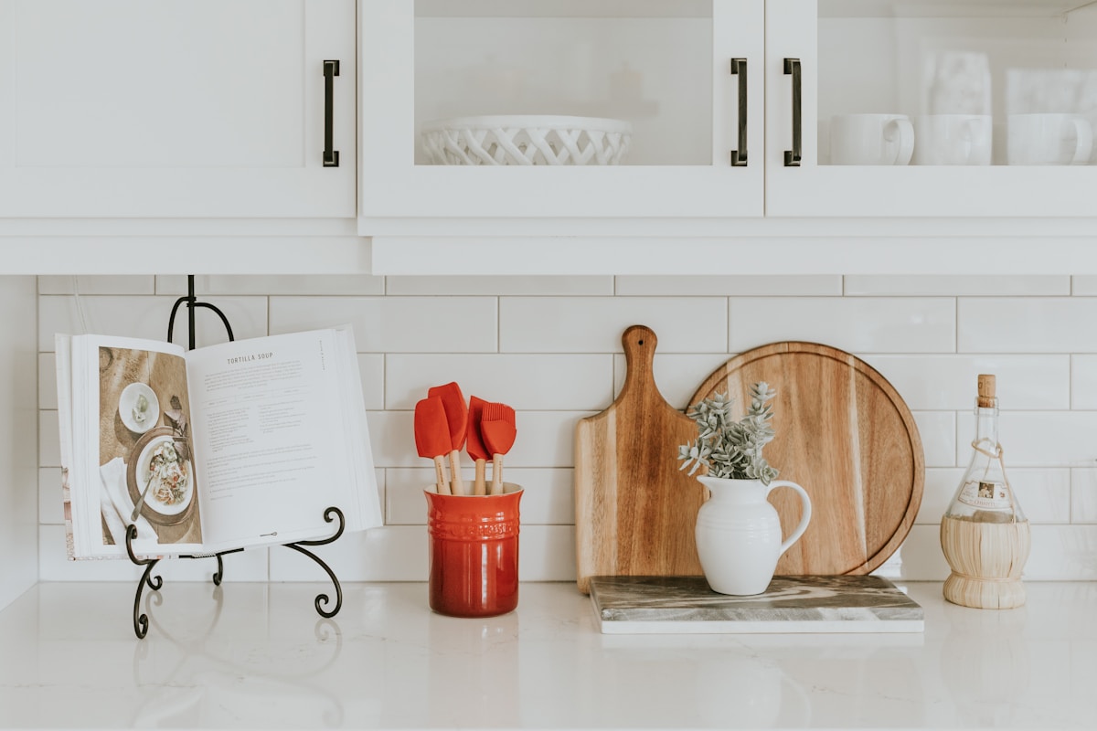 Cuisine blanche moderne avec accessoires décoratifs en bois et rouge.