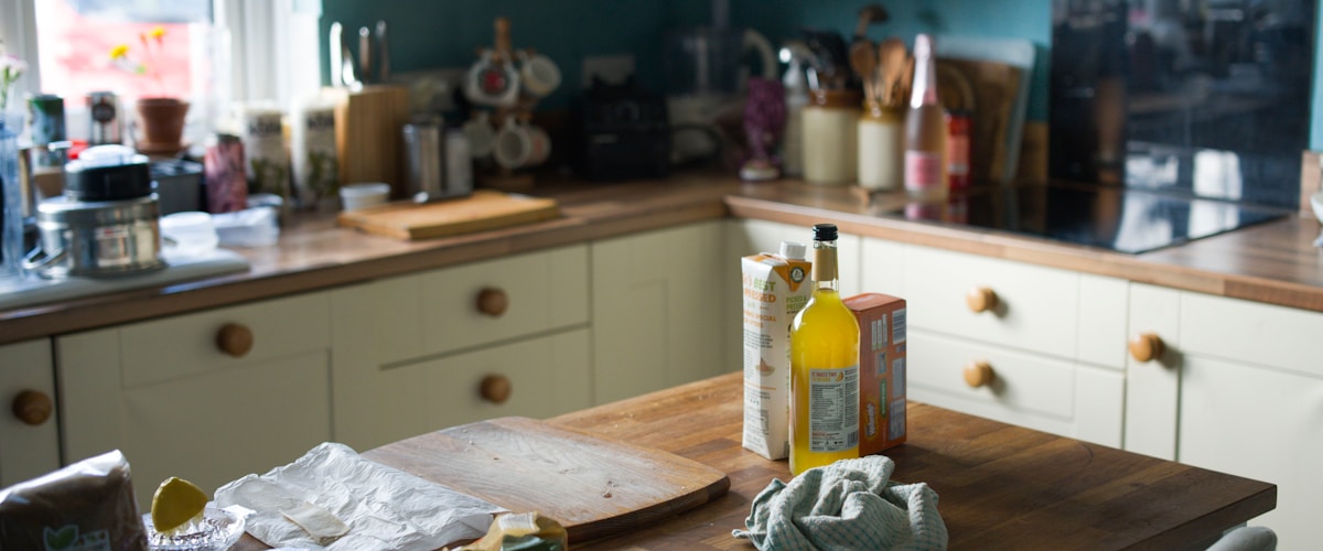 Cuisine désordonnée avec ustensiles, bouteille d'huile et planche à découper.