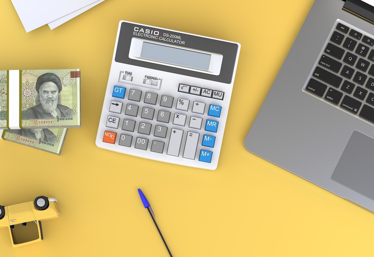 Bureau de travail avec calculatrice, ordinateur portable et billets de banque.