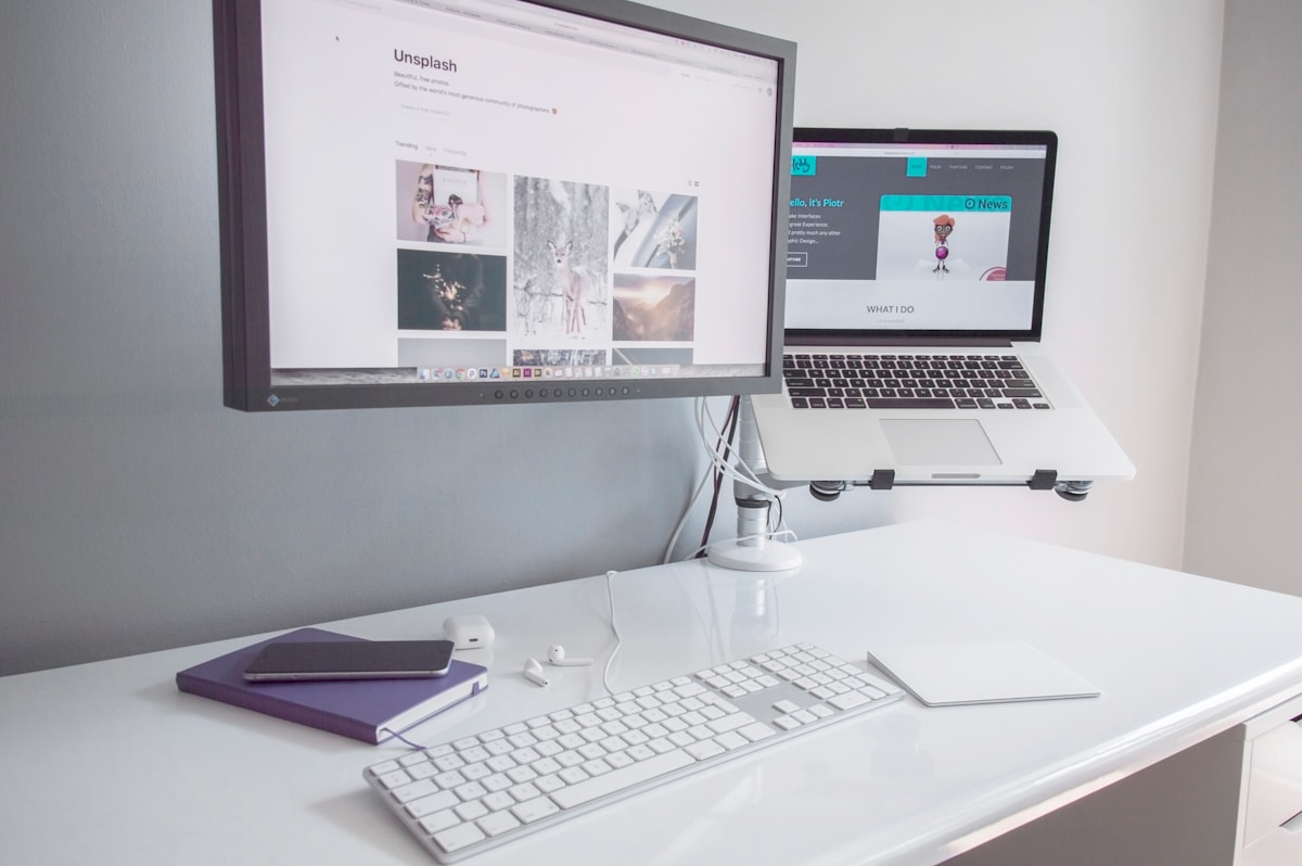 Bureau de travail avec ordinateur portable, clavier, écran et accessoires.