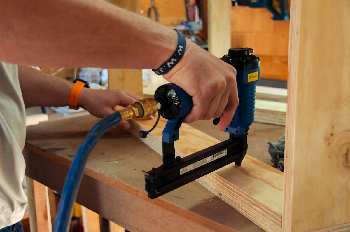 Personne utilisant un cloueur pneumatique pour assembler du bois.