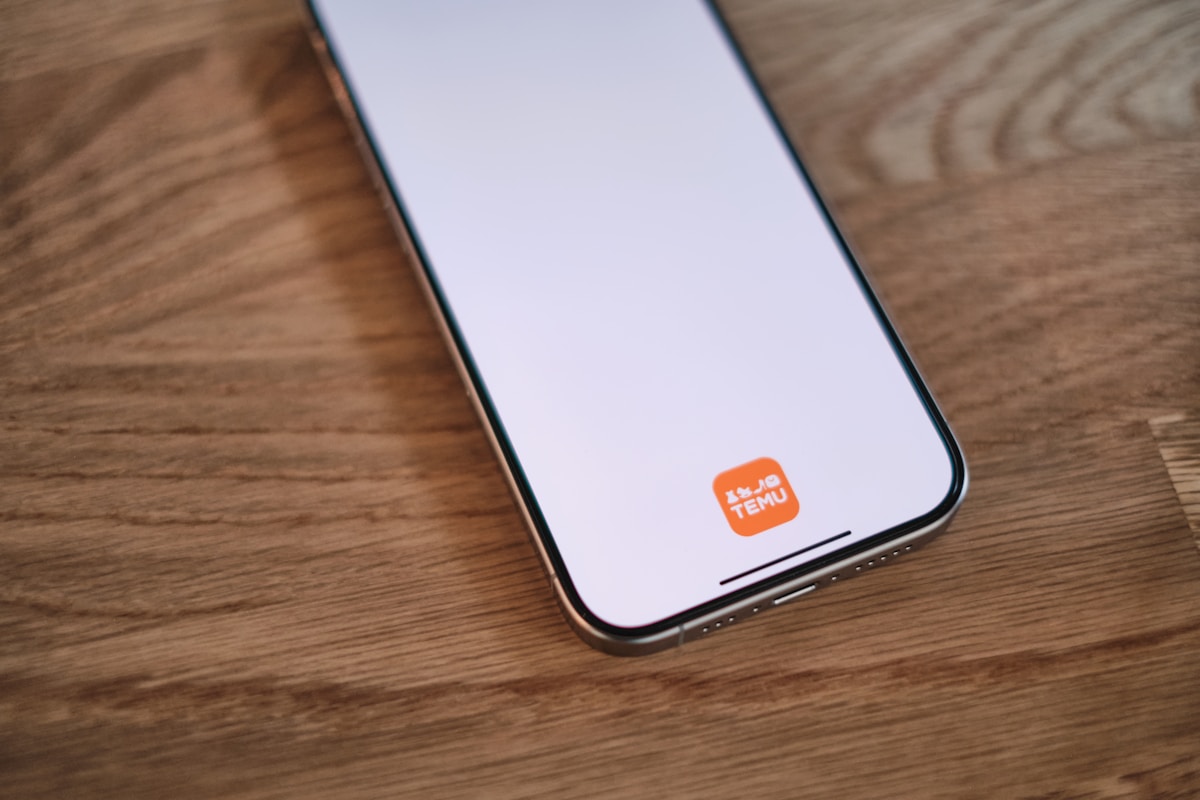 Smartphone avec logo orange de l'application Temu sur l'écran.