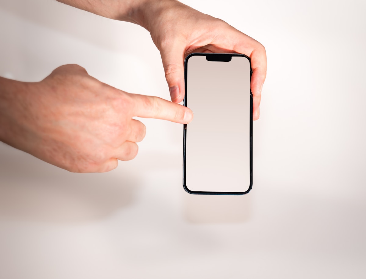 Mains tenant un smartphone avec écran blanc.