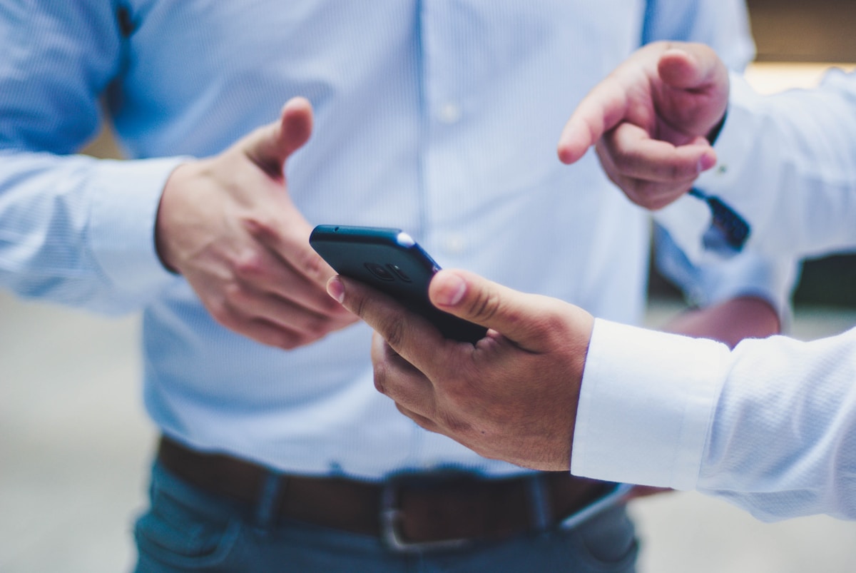 Deux personnes en costume échangeant des informations sur un smartphone.