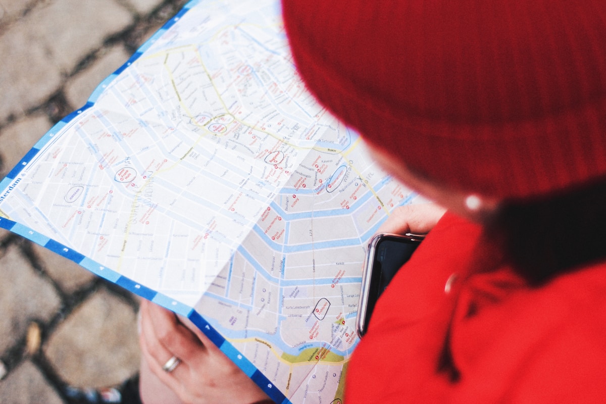 Personne en veste rouge examinant une carte de ville.