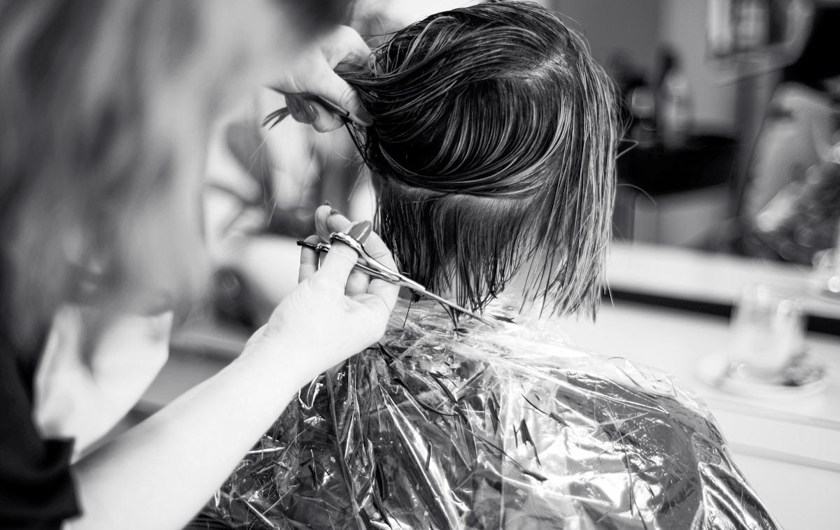 Coiffure en noir et blanc, mains coupant les cheveux avec des ciseaux.