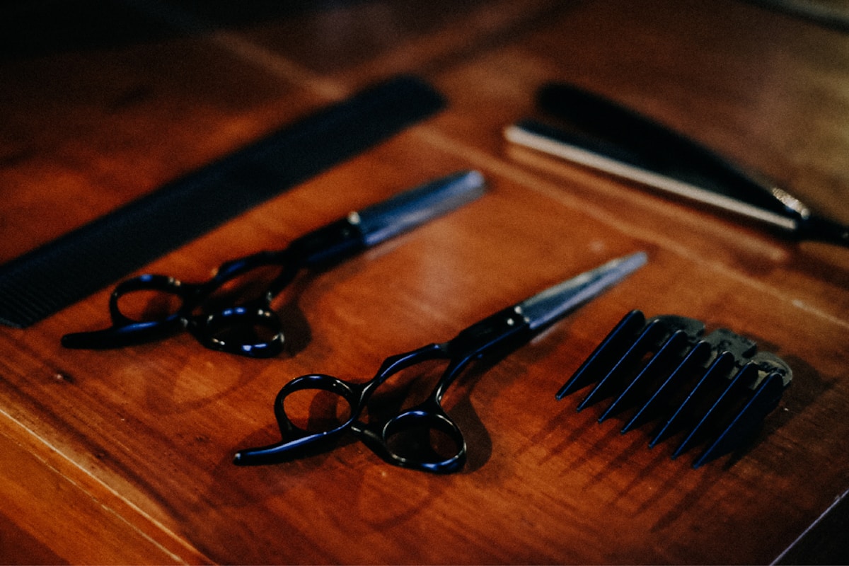 Ciseaux de coiffure noirs sur une surface en bois.