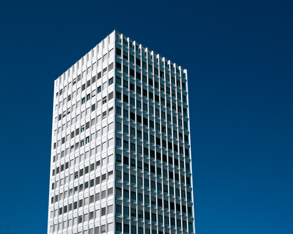 Gratte-ciel moderne à structure géométrique sur fond de ciel bleu.