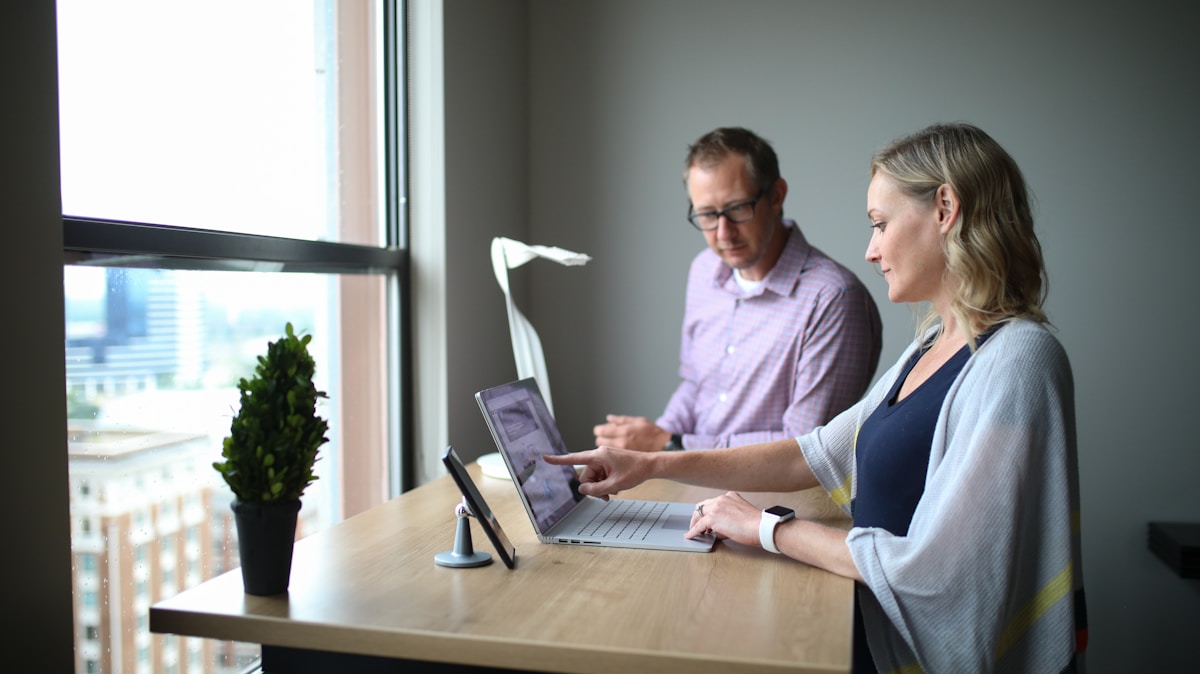 Deux personnes travaillant ensemble sur un ordinateur portable dans un bureau.