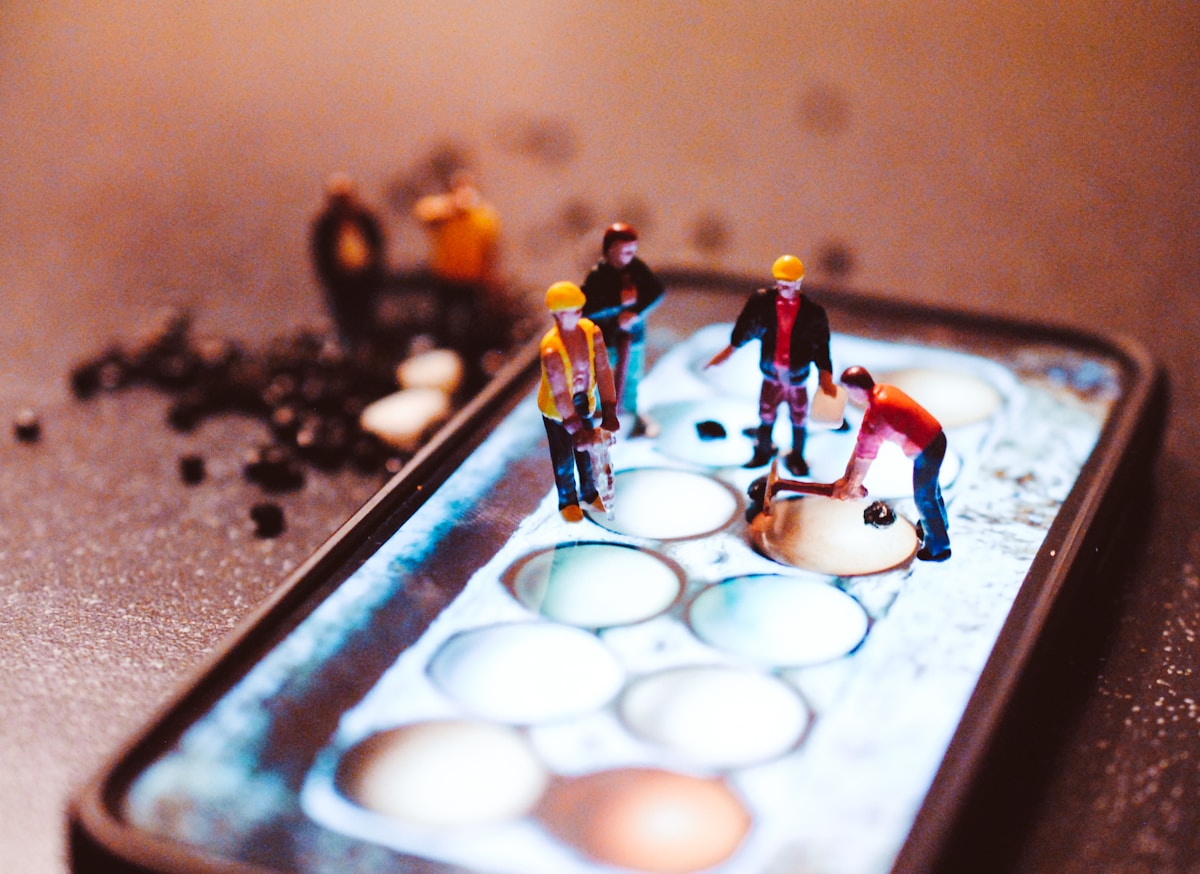 Figurines miniatures sur un plateau avec des œufs et des ingrédients.