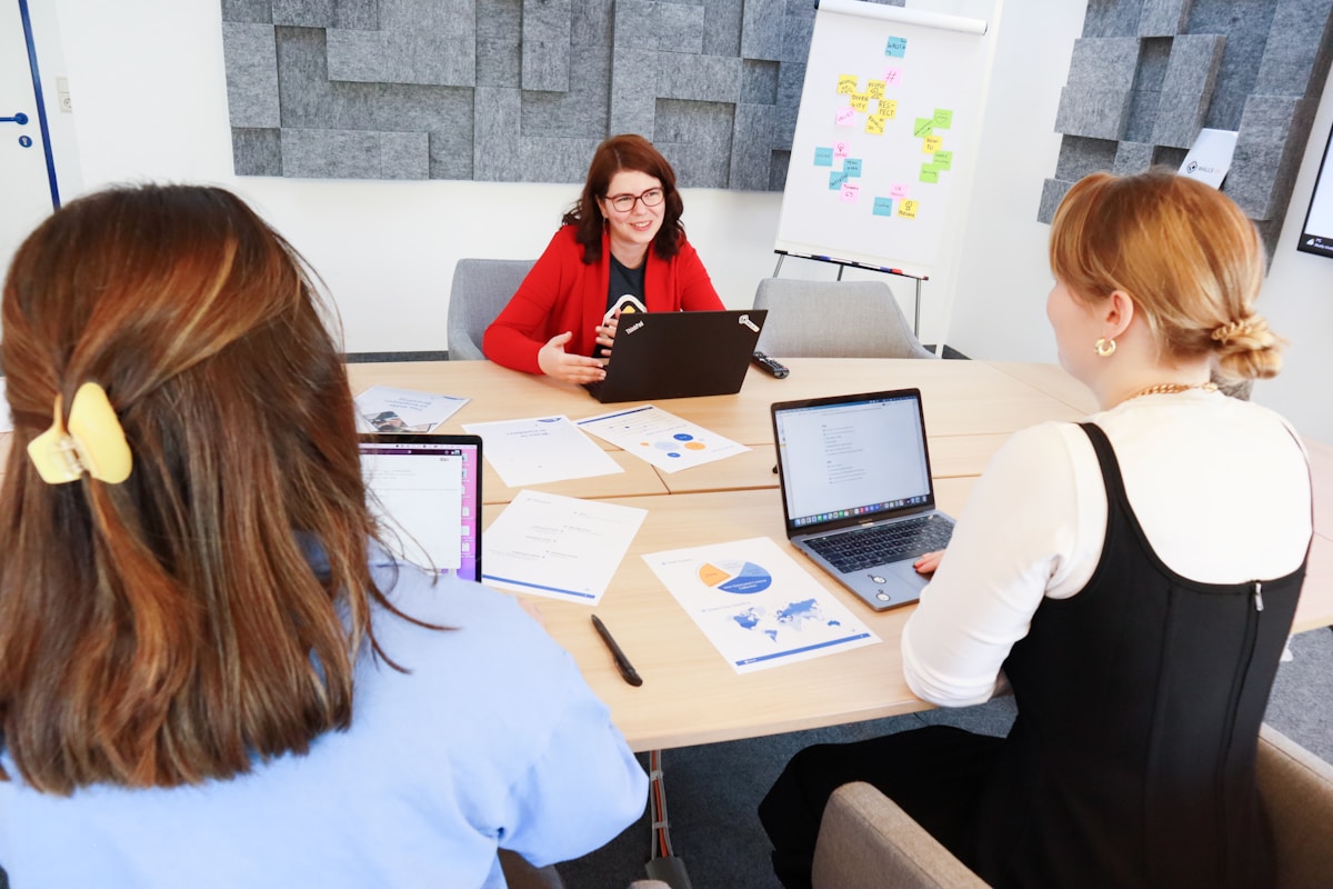 Réunion de travail dans un bureau moderne avec des employés utilisant des ordinateurs portables.