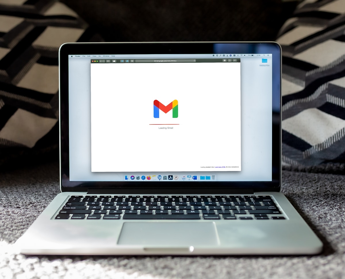 Ordinateur portable affichant le logo de Gmail sur un écran blanc.
