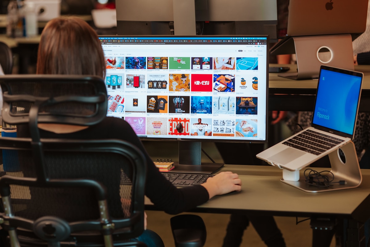 Personne travaillant sur ordinateur dans un espace de travail encombré.