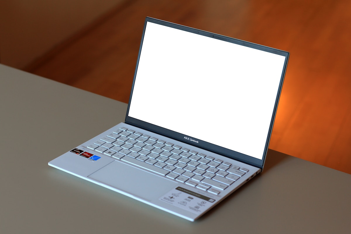 Ordinateur portable Asus Zenbook avec écran blanc et clavier argenté.