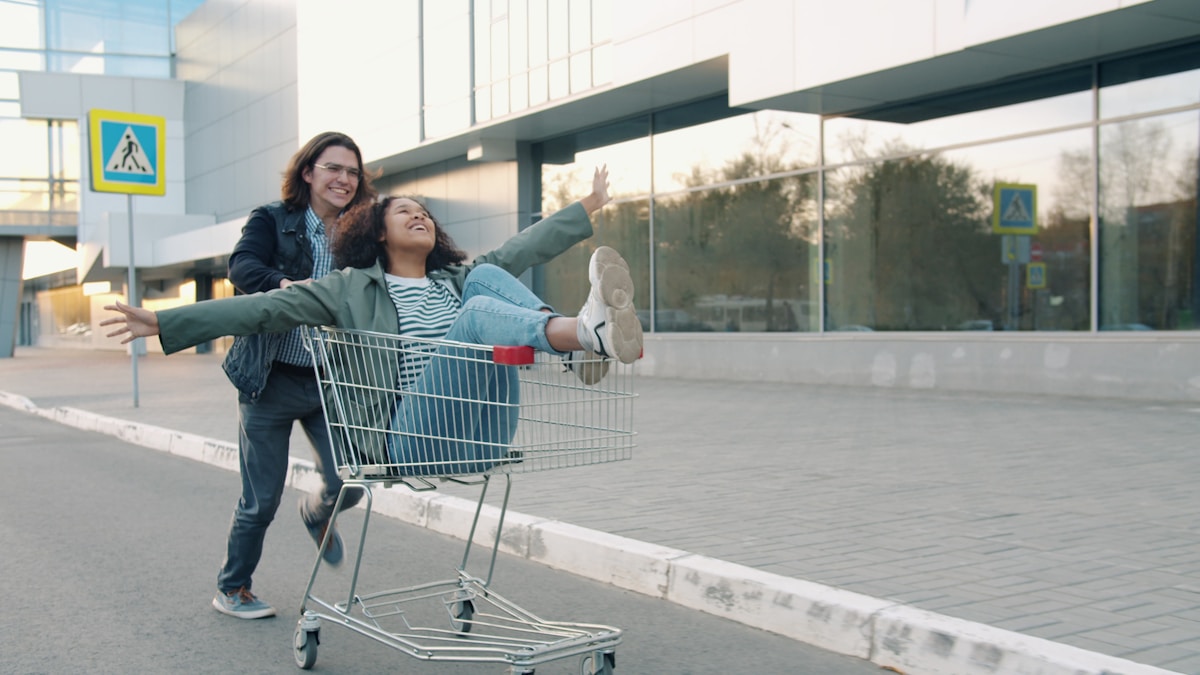 Deux femmes joyeuses dans un chariot de supermarché à l'extérieur.