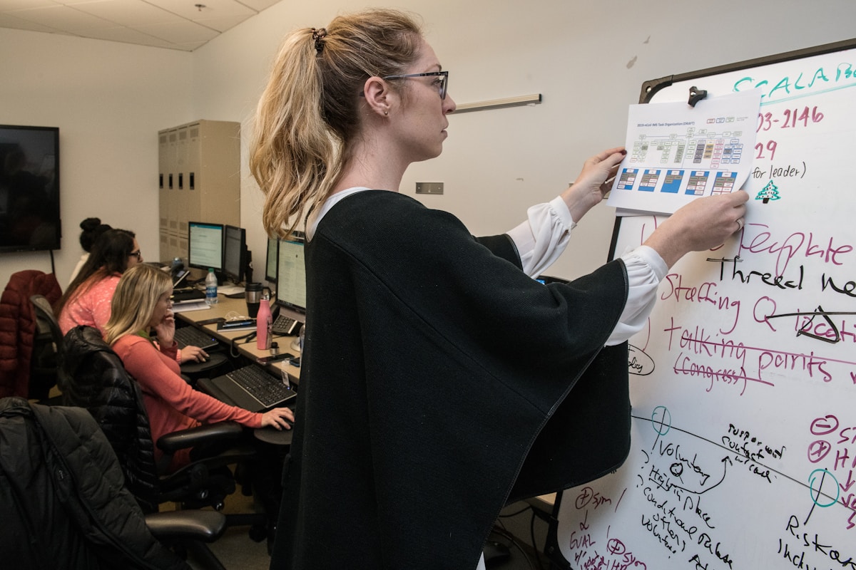 Femme écrivant sur un tableau blanc dans un bureau.