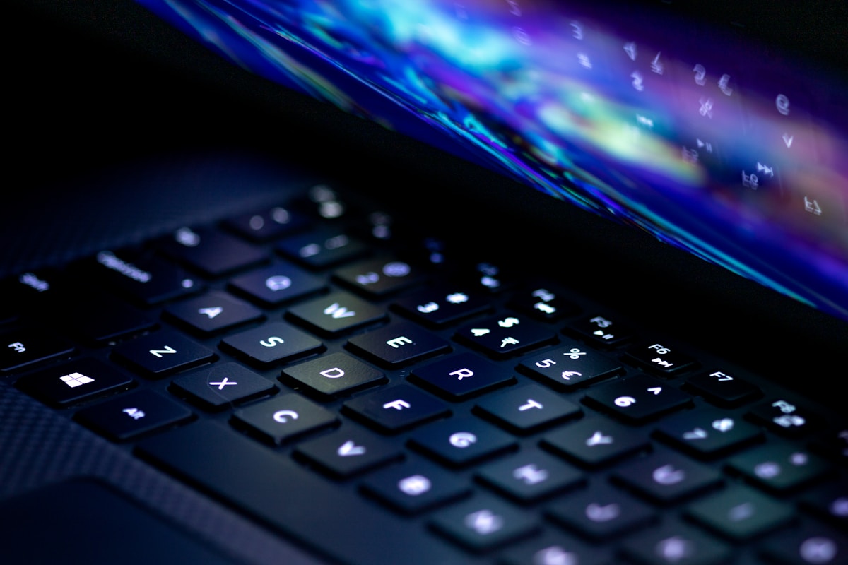 Clavier d'ordinateur avec effets lumineux bleutés et violets.