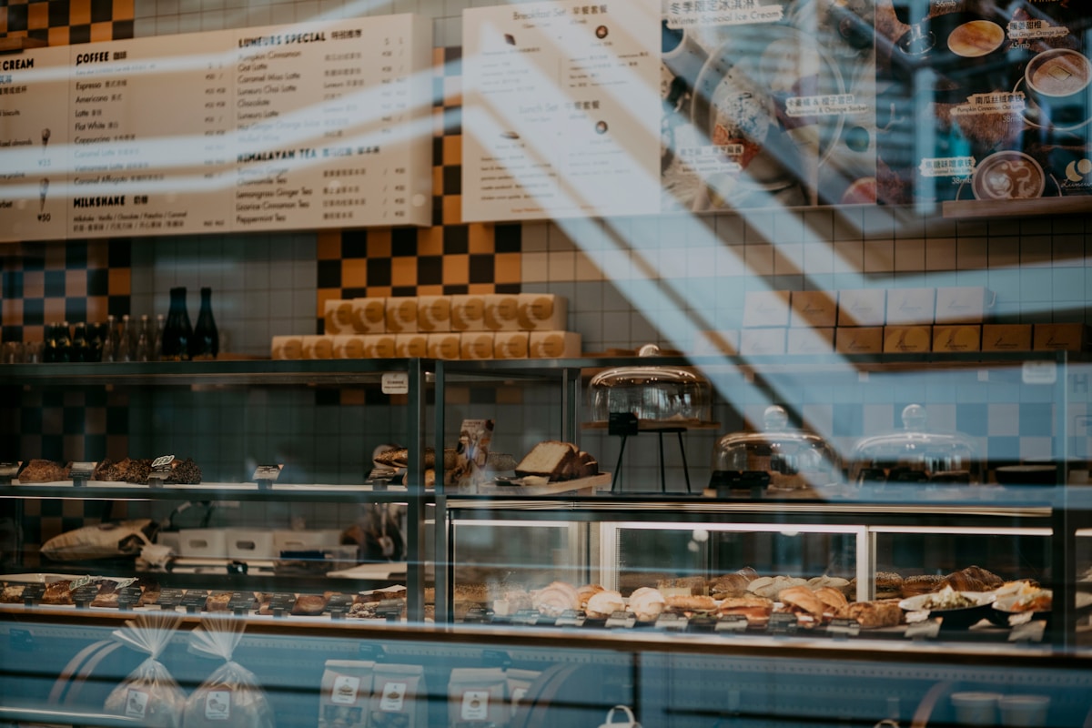 Vitrine de boulangerie-pâtisserie avec une variété de pâtisseries et de boissons.