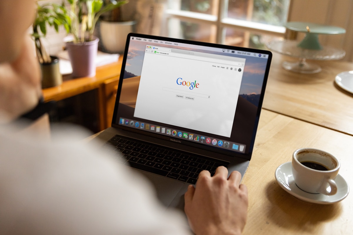 Ordinateur portable avec le moteur de recherche Google sur l'écran, sur un bureau avec une tasse de café.