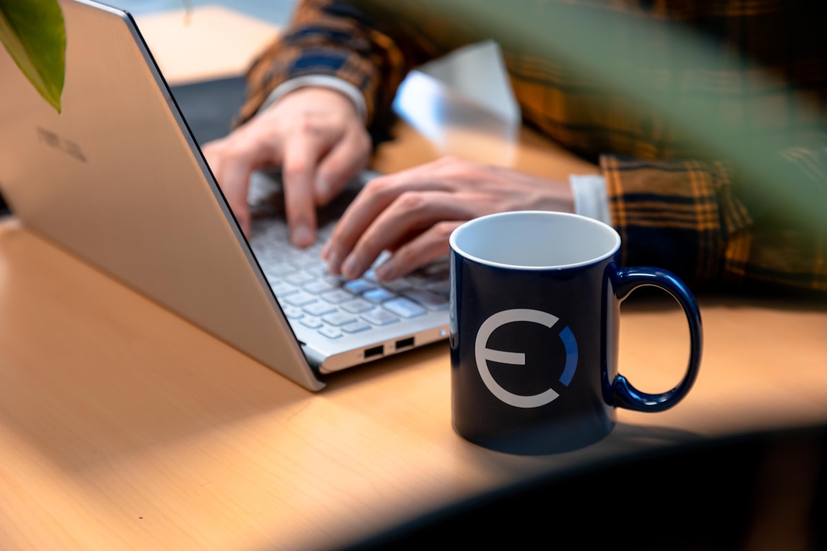 Ordinateur portable, tasse de café, mains tapant sur le clavier.