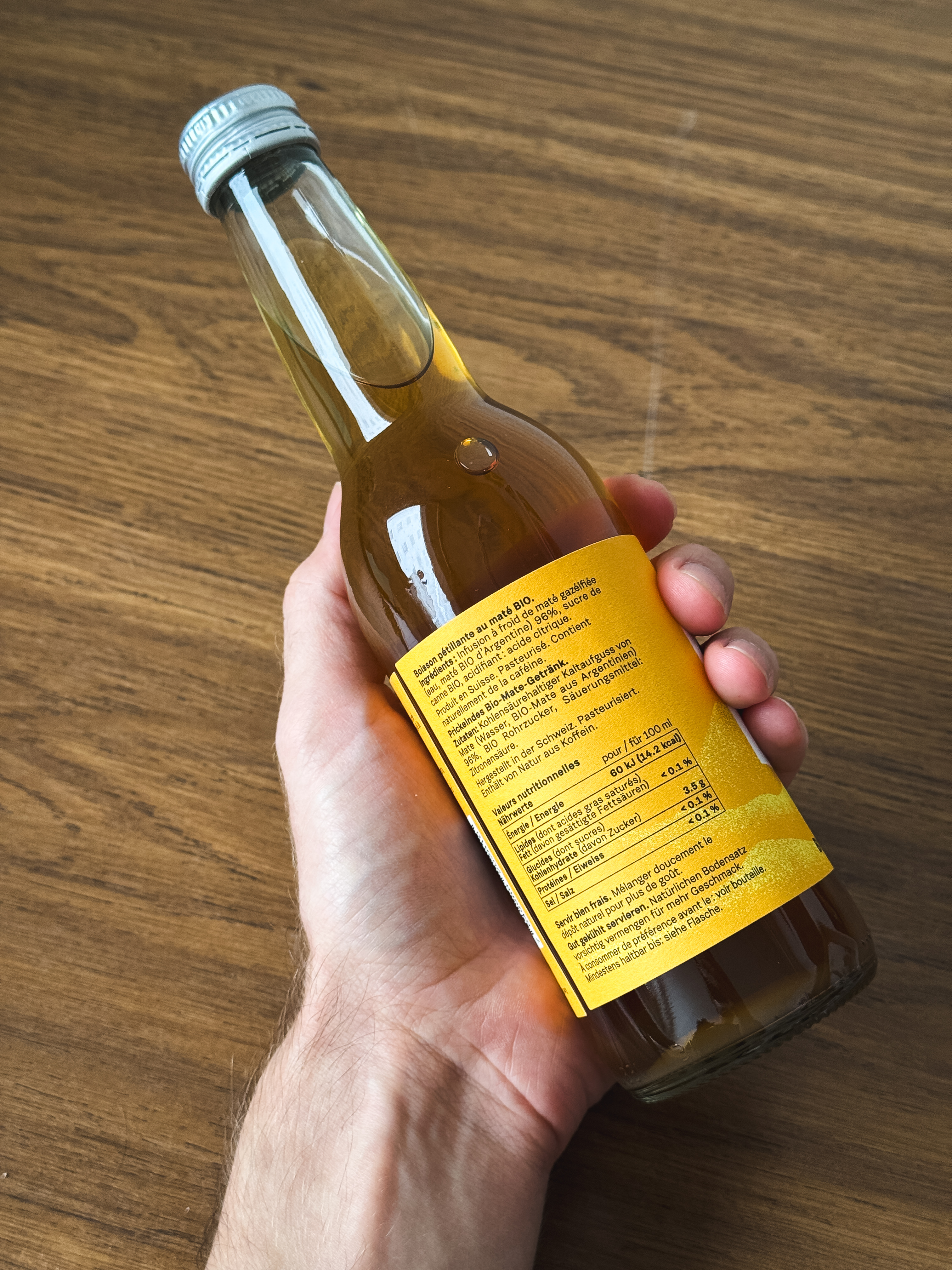 Une personne tenant une bouteille de boisson, avec l'accent mis sur l'étiquette nutritionnelle.