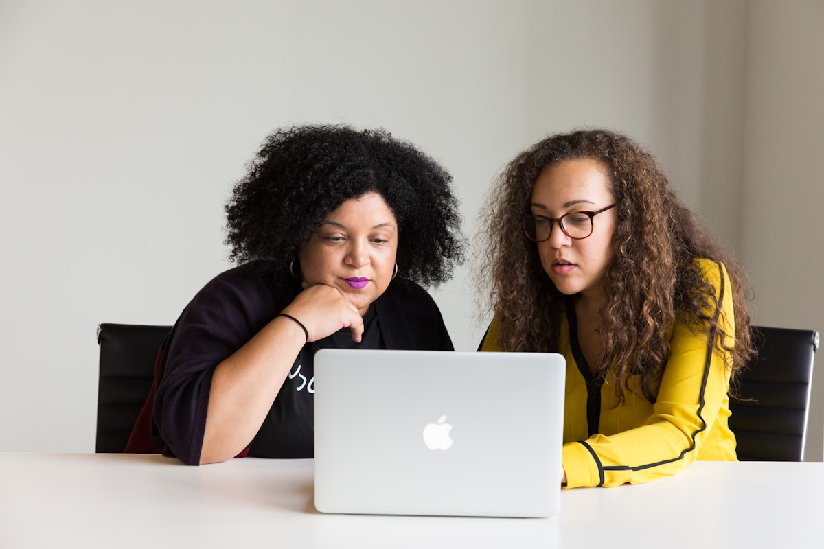 Deux femmes travaillant ensemble sur un ordinateur portable.
